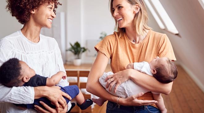 Two mothers holding their sleeping infants together in community