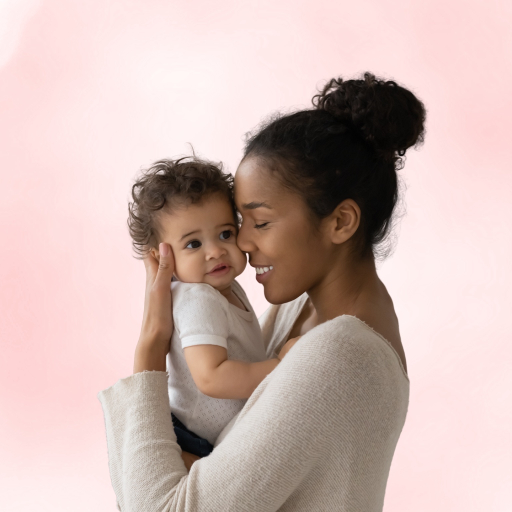 A mother smiling tenderly as she holds her baby close to her cheek in a loving embrace